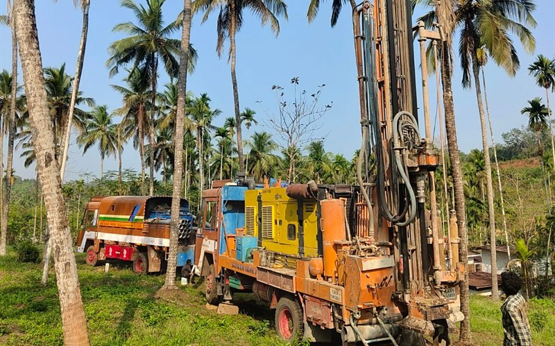 Agricultural borewell drilling rig truck and compressor operating on coconut and arecanut plantation in Taliparamba, Kerala